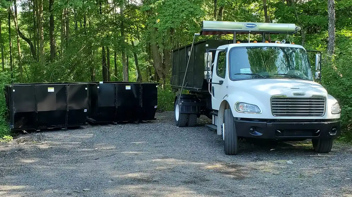 Dumpster Solutions roll-off truck loading a 20-yard container